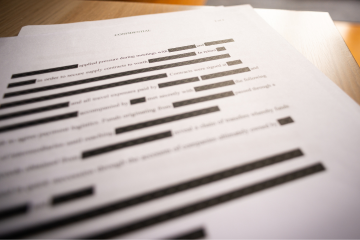 Black redacted text on a document of white paper